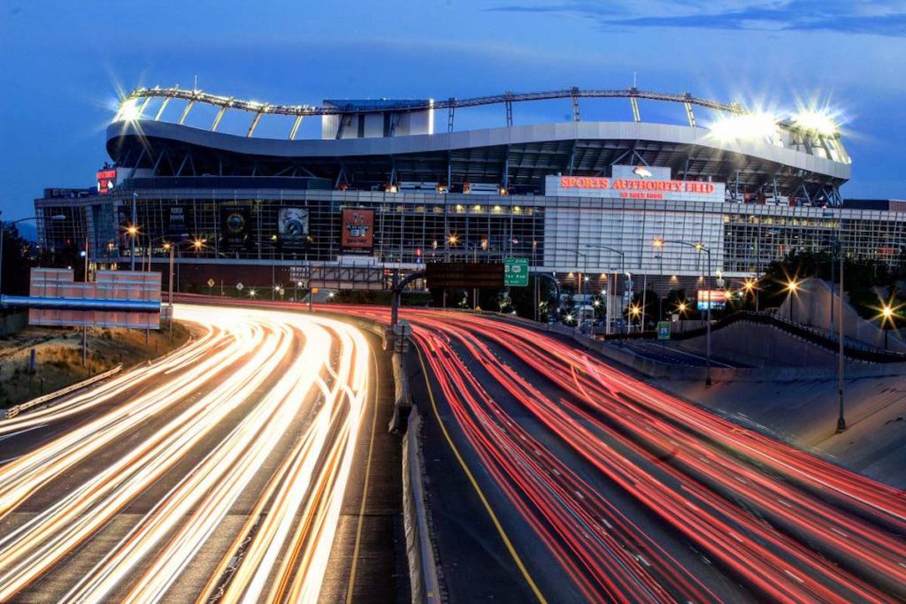 Bronco Stadium at dusk with headlights and tailights speeding by