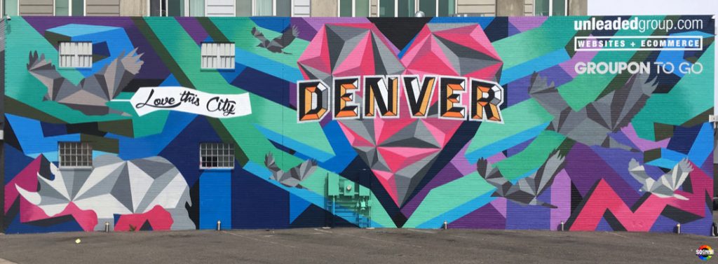 Love This City mural includes geomtetic designs using pink, grey, teal, blue and purple. Features a heart, rhino, birds and the words "Love this City Denver"